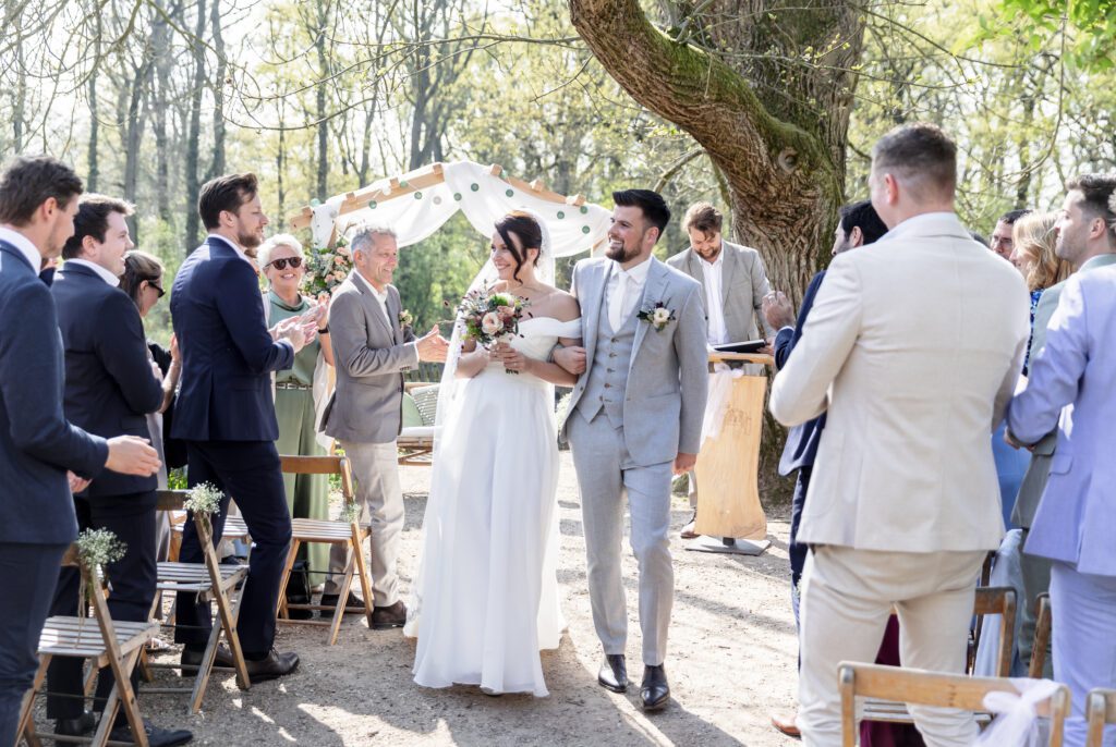 bruidspaar loopt door het gangpad met bellenblaas en confetti